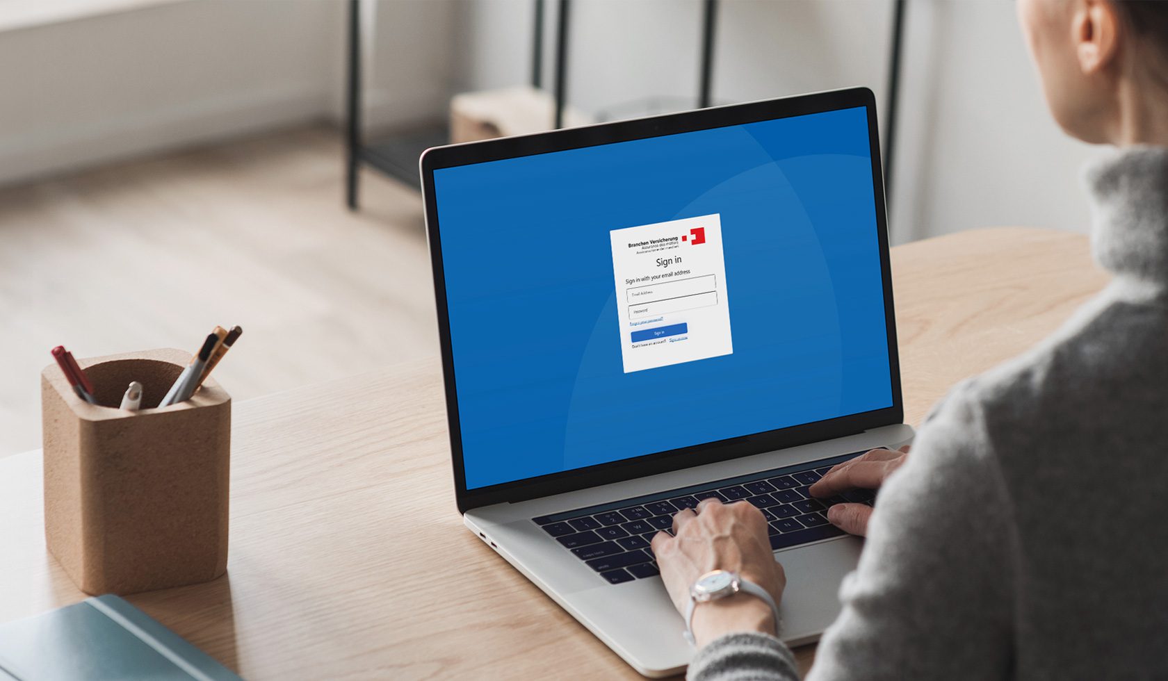 Blick über die Schulter einer Frau auf den Screen eines LapTops. Auf dem Screen sieht man die Startseite des eLM der Branchen Versicherung.